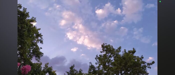 Nubes rosadas sobre un cielo azul con árboles verdes