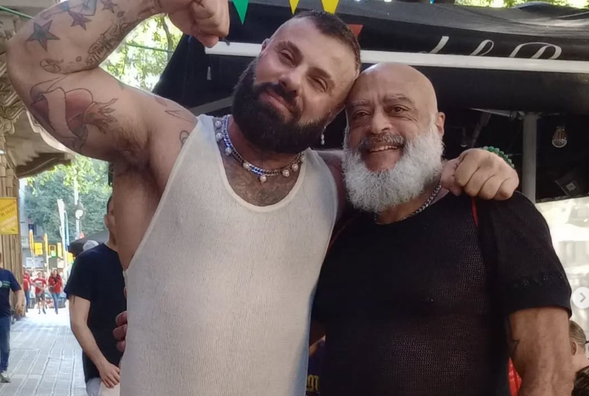 2025-07-15 204321 Dos personas abrazadas y sonrientes posan en la calle durante un evento en Barcelona. Una de ellas es Alex Marte, reconocido por su trayectoria artística.